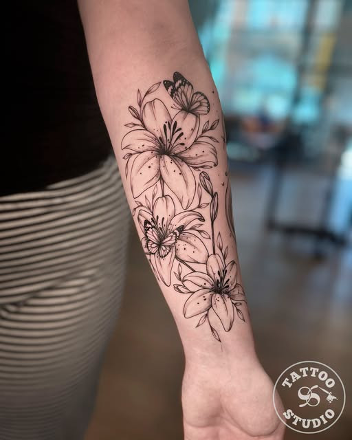 Tattoo Studio 96 Aalborg viser et fine line-design med liljer og sommerfugle